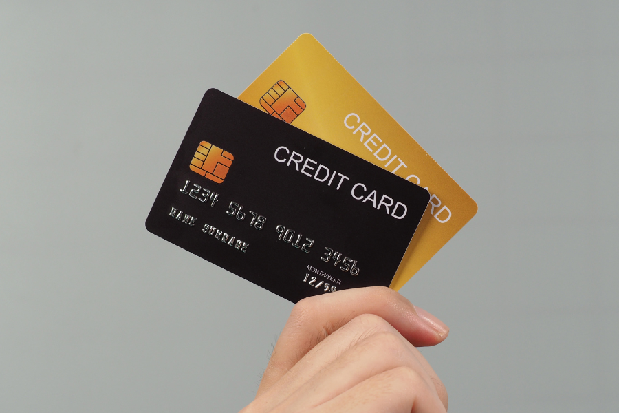Mão a segurar cartões de crédito, ilustrando soluções de crédito pessoal e gestão financeira responsável.